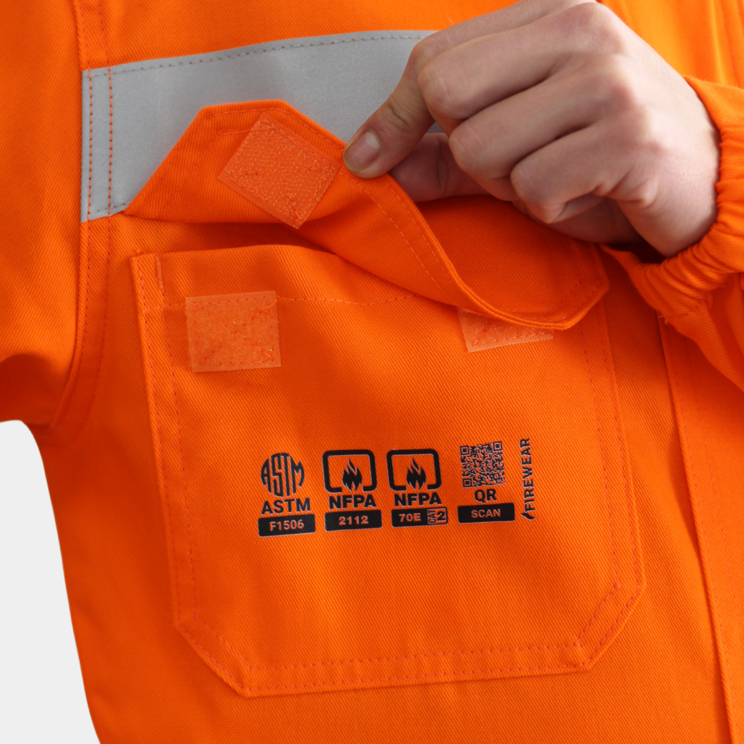 Detalle de bolsillo de pecho de overol ignífugo FIREWEAR® naranjo para hombre.