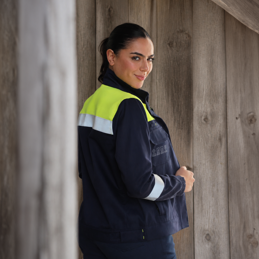 Mujer usando chaqueta ignífuga FIREWEAR® bicolor durante una jornada industrial.