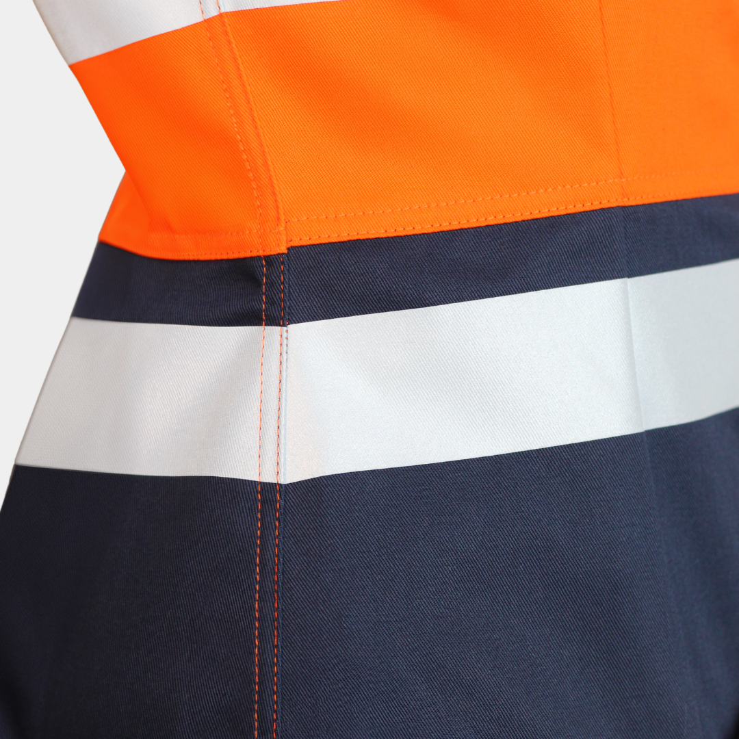 Detalle de cinta reflectante de blusa ignífuga FIREWEAR® bicolor naranjo y azul para mujer.