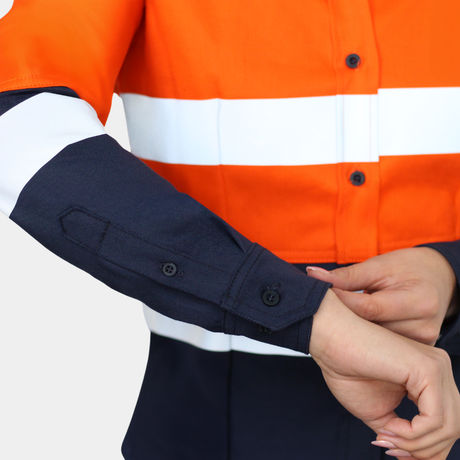 Detalle de puño de blusa ignífuga FIREWEAR® bicolor naranjo y azul para mujer.
