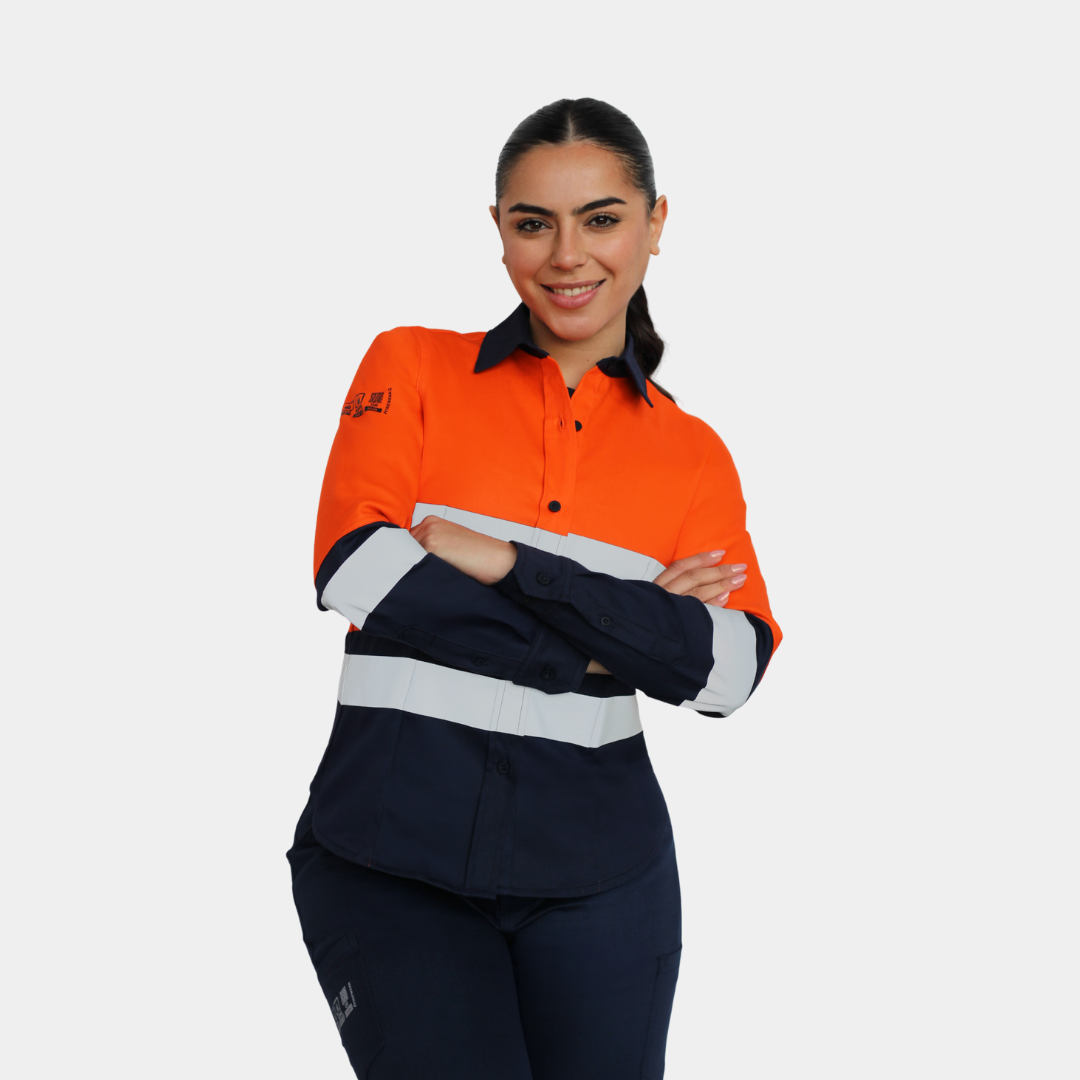 Mujer usando blusa ignífuga FIREWEAR® bicolor naranjo y azul con brazos cruzados.