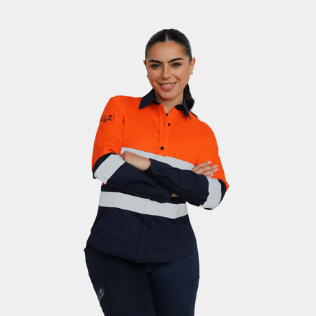 Mujer usando blusa ignífuga FIREWEAR® bicolor naranjo y azul con brazos cruzados.