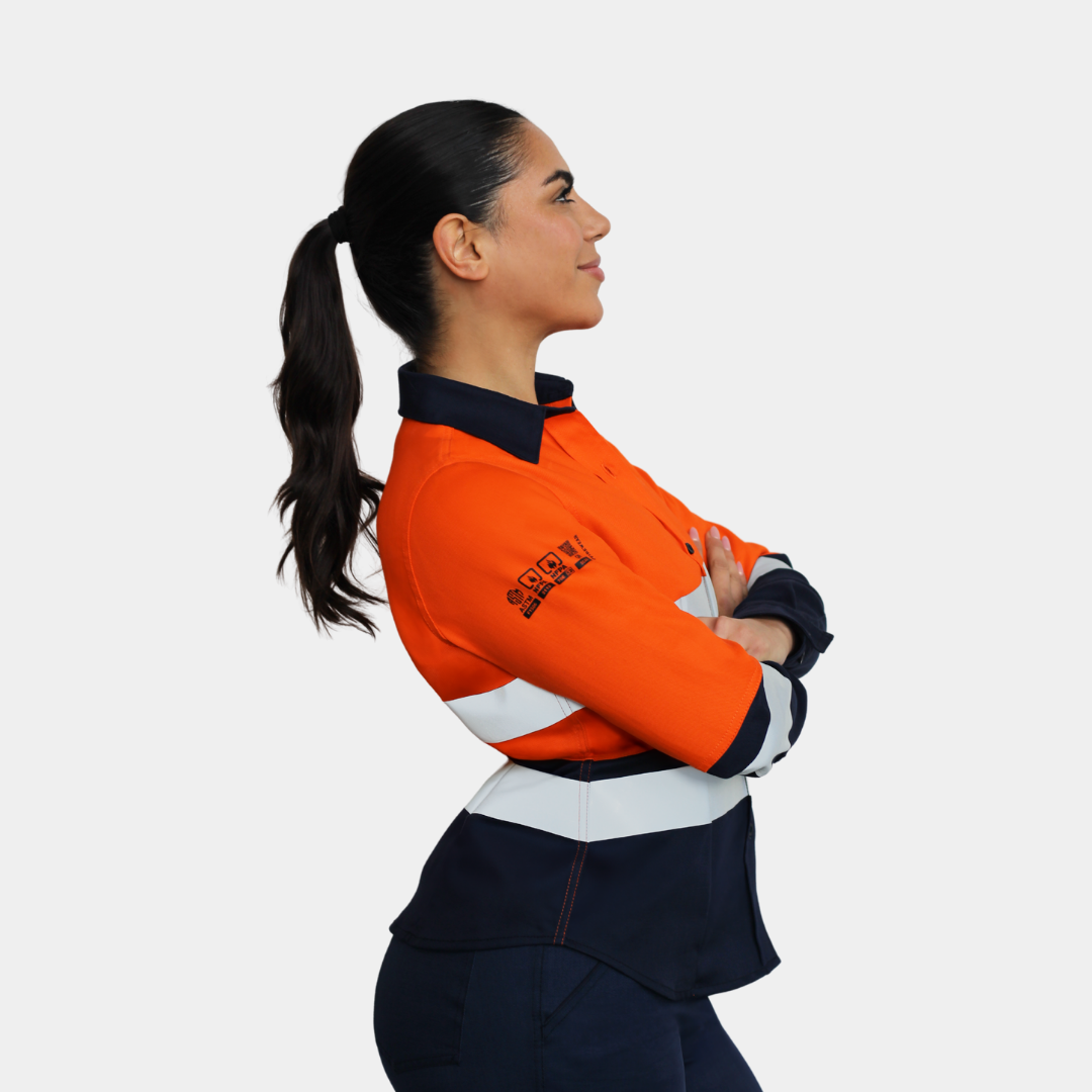 Mujer usando blusa ignífuga FIREWEAR® bicolor naranjo y azul en vista lateral.