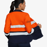 Mujer usando blusa ignífuga FIREWEAR® bicolor naranjo y azul en vista posterior tres cuartos.
