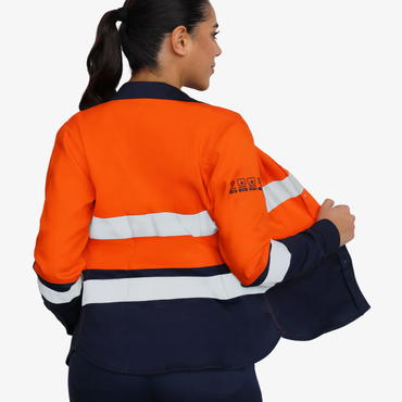 Mujer usando blusa ignífuga FIREWEAR® bicolor naranjo y azul en vista posterior tres cuartos.