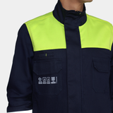 Detalle de bolsillos de pecho de chaqueta ignífuga FIREWEAR® bicolor azul y amarillo para hombre.