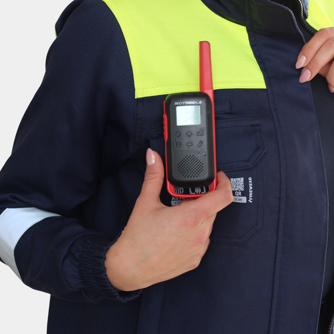 Detalle de bolsillo para radio de chaqueta ignífuga FIREWEAR® bicolor azul y amarillo para mujer.