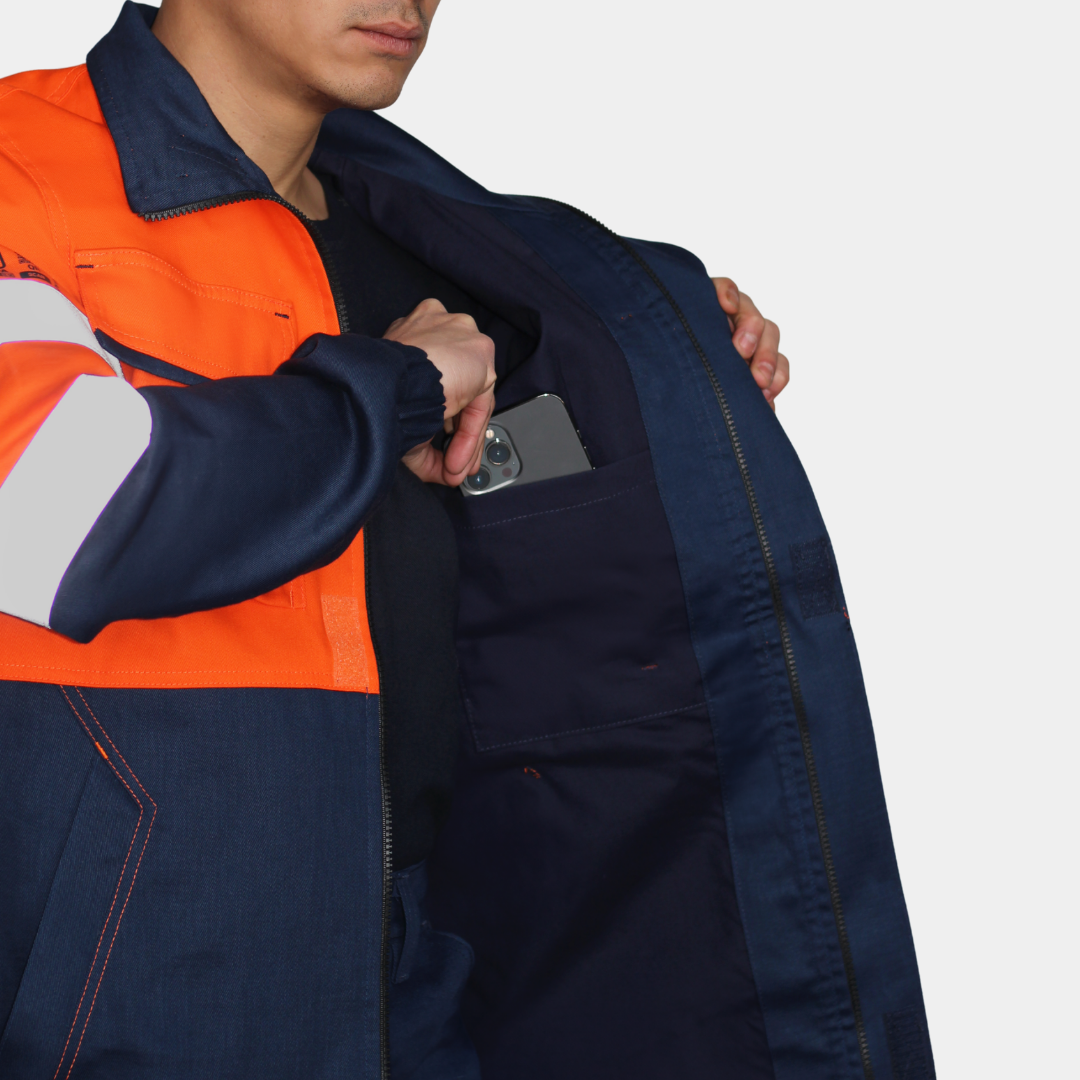 Detalle de bolsillo interior de chaqueta ignífuga FIREWEAR® bicolor naranjo y azul para hombre.