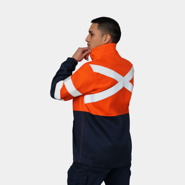 Hombre usando chaqueta ignífuga FIREWEAR® bicolor naranjo y azul en vista posterior tres cuartos.