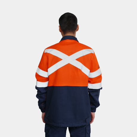 Hombre usando chaqueta ignífuga FIREWEAR® bicolor naranjo y azul en vista posterior.