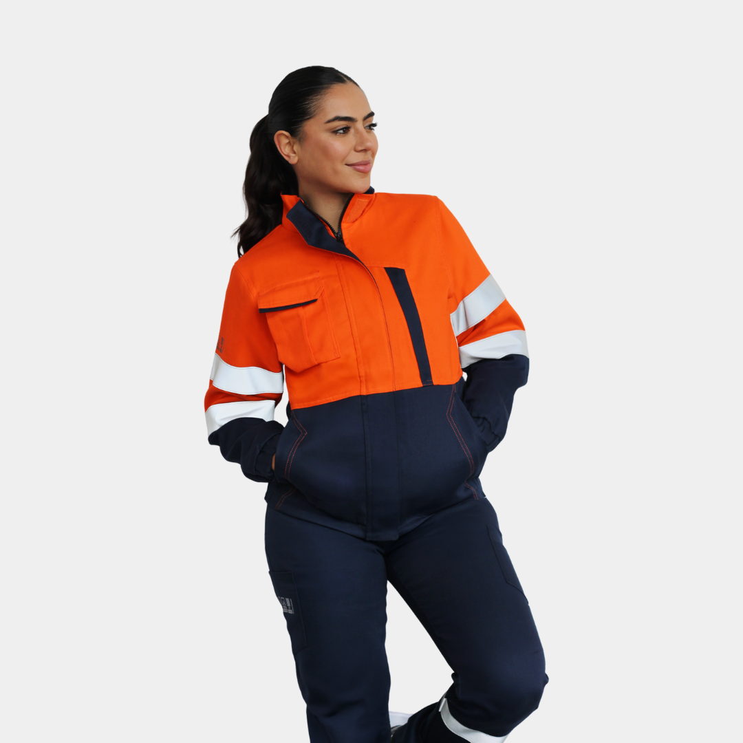 Mujer usando chaqueta ignífuga FIREWEAR® bicolor naranjo y azul en vista frontal de cuerpo completo.