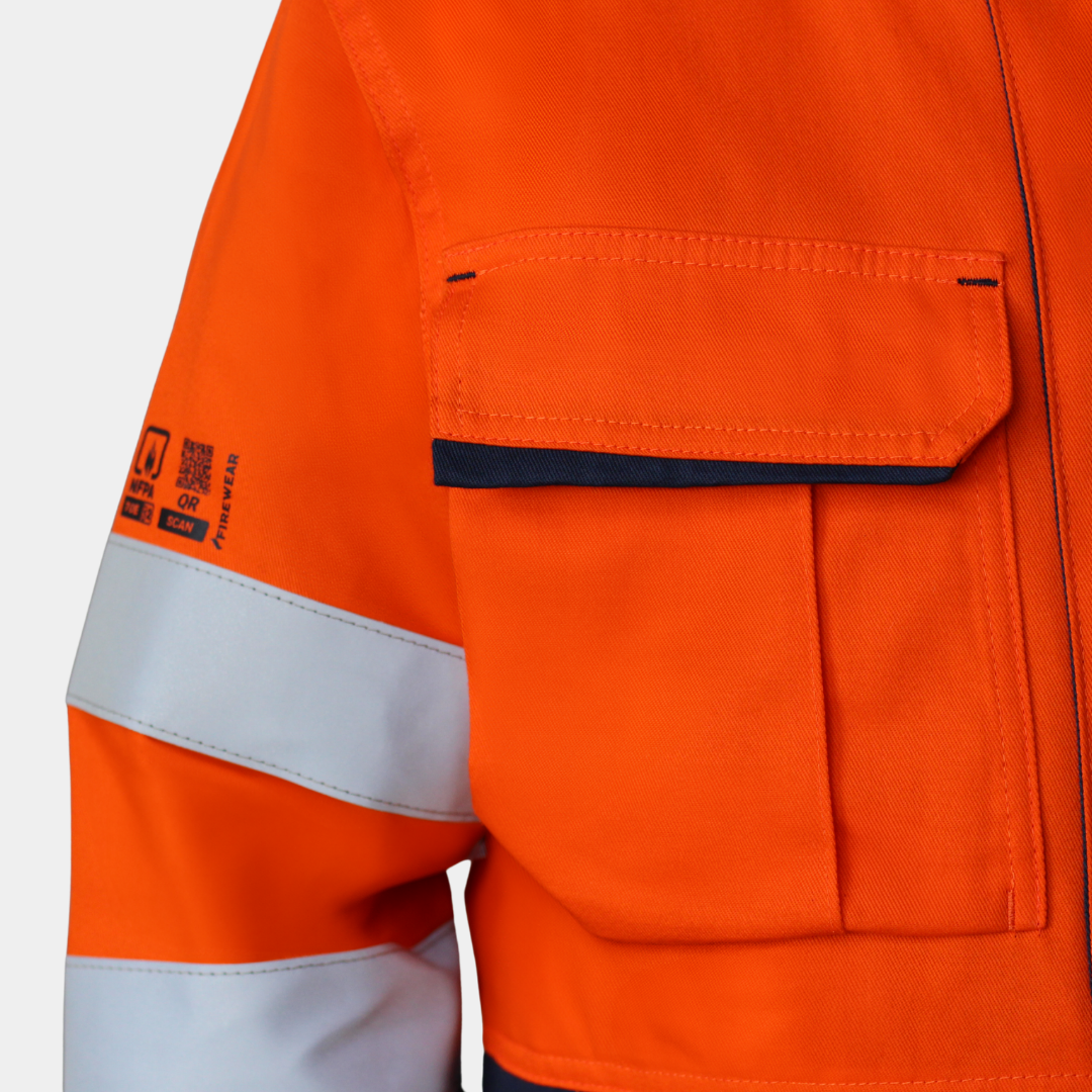 Detalle de bolsillo de pecho de chaqueta térmica ignífuga FIREWEAR® bicolor naranjo y azul para hombre.