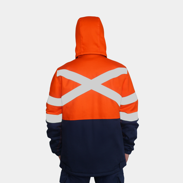 Hombre usando chaqueta térmica ignífuga FIREWEAR® bicolor naranjo y azul en vista posterior con capucha.