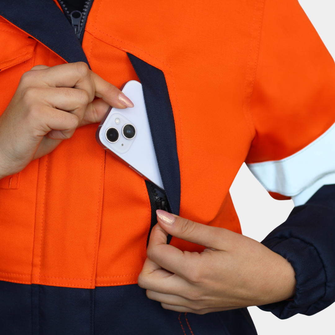 Detalle de bolsillo de pecho de chaqueta térmica ignífuga FIREWEAR® bicolor naranjo y azul para mujer.