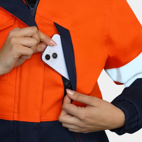 Detalle de bolsillo de pecho de chaqueta térmica ignífuga FIREWEAR® bicolor naranjo y azul para mujer.