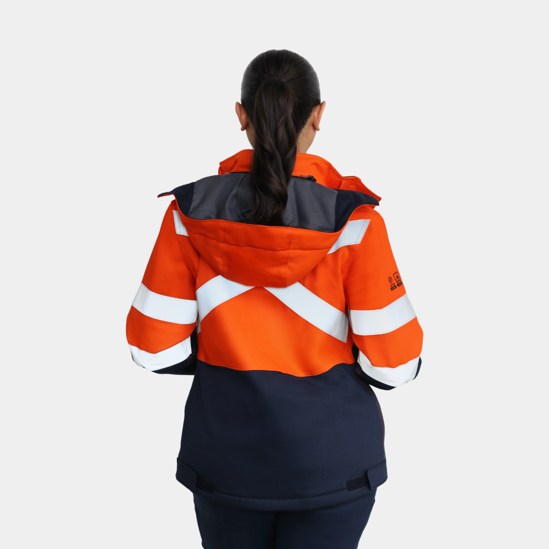 Mujer usando chaqueta térmica ignífuga FIREWEAR® bicolor naranjo y azul en vista posterior con capucha.
