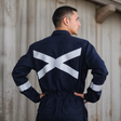 Hombre usando overol ignífugo FIREWEAR® azul marino en vista posterior durante trabajo industrial.