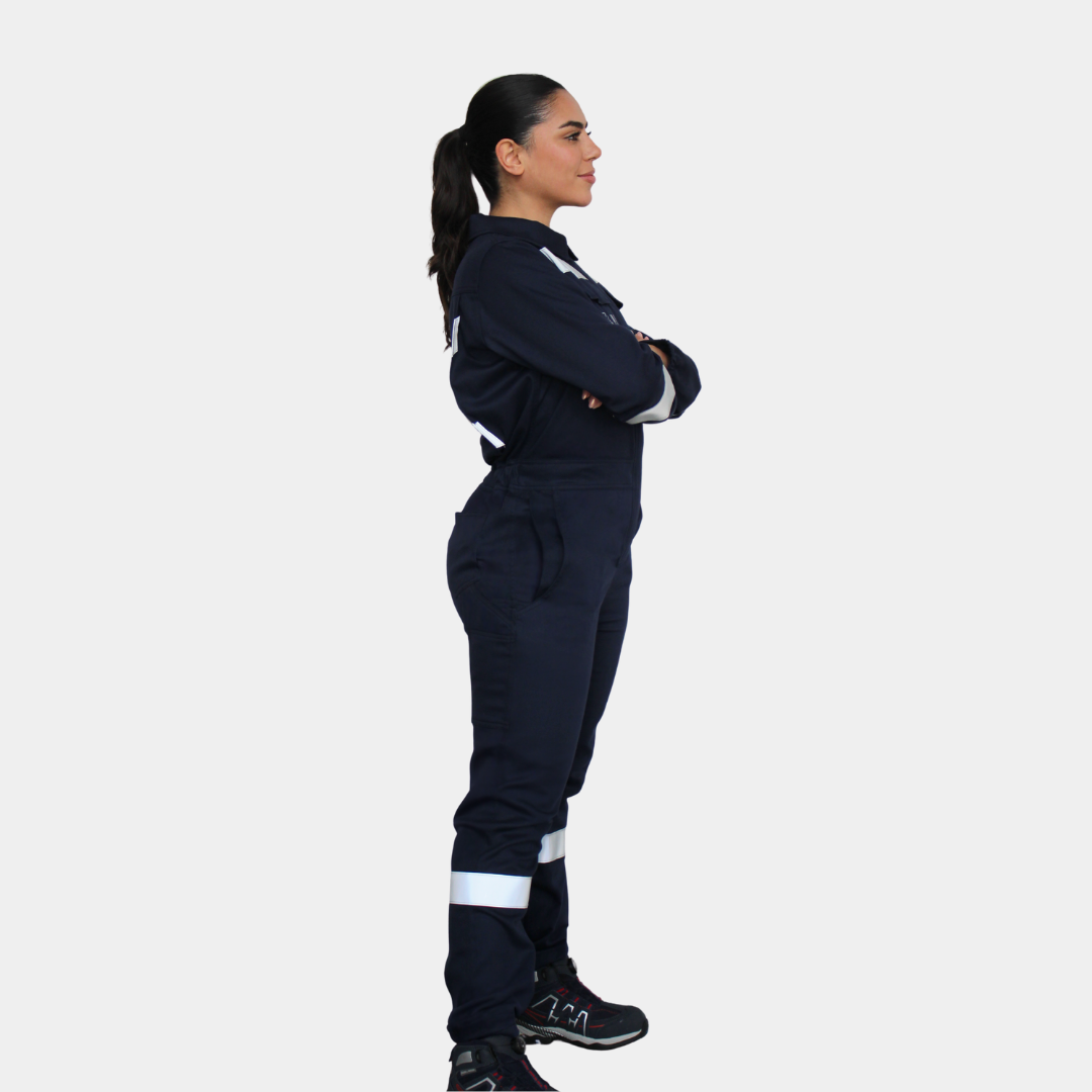Mujer usando overol ignífugo FIREWEAR® azul marino en vista lateral de cuerpo completo.