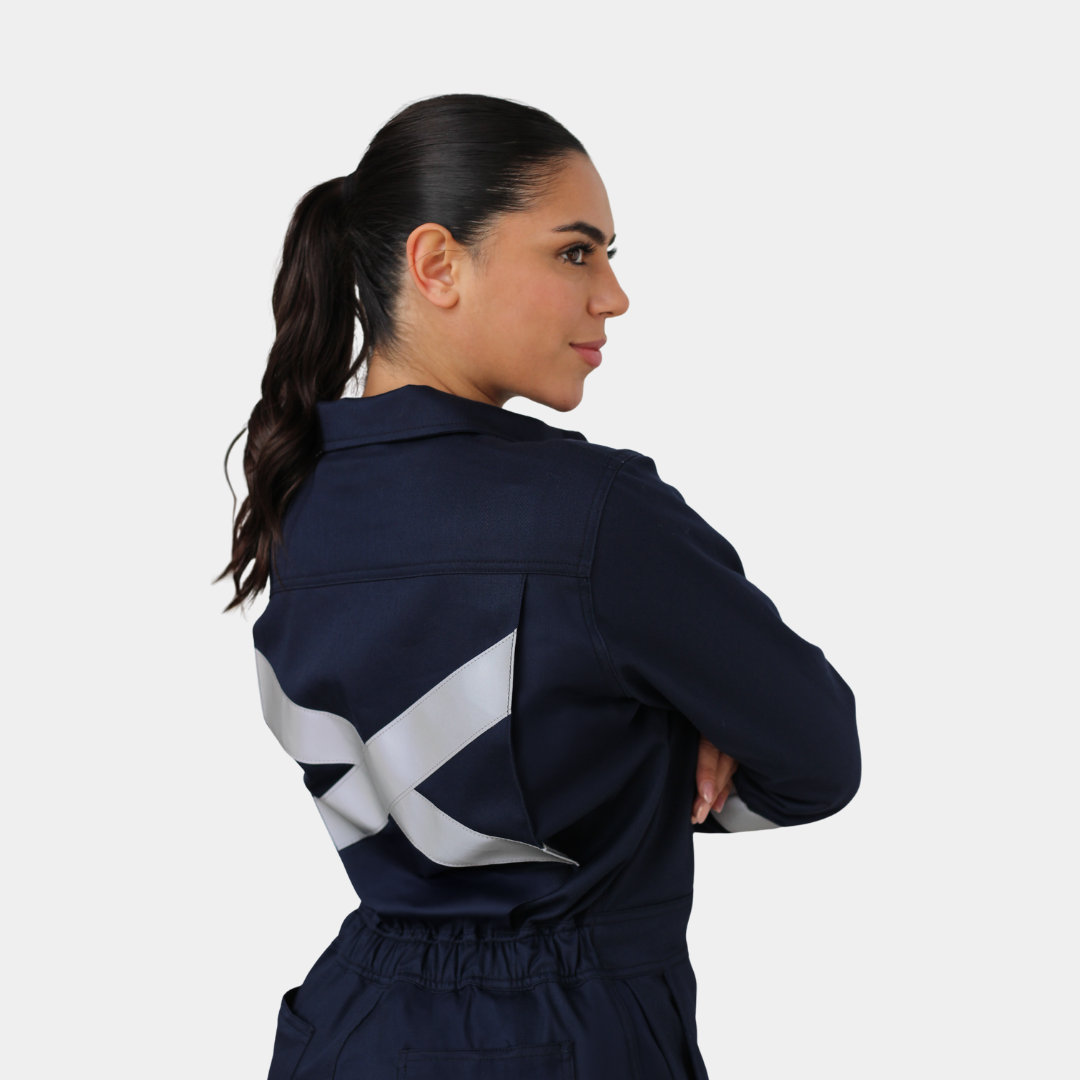 Mujer usando overol ignífugo FIREWEAR® azul marino en vista posterior tres cuartos.
