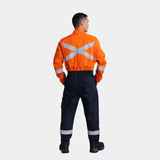Hombre usando overol ignífugo FIREWEAR® bicolor naranjo y azul en vista posterior.