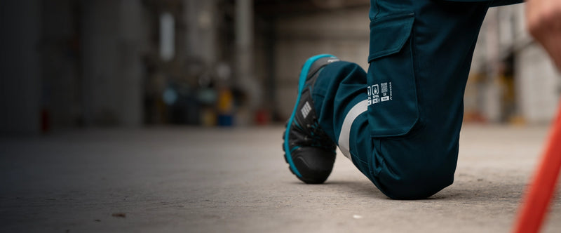 Trabajador usando pantalón ignífugo FIREWEAR® azul marino en posición de rodillas.