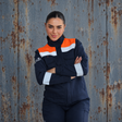 Mujer usando chaqueta ignífuga FIREWEAR® azul marino y naranja de VITATEX con cintas reflectantes.